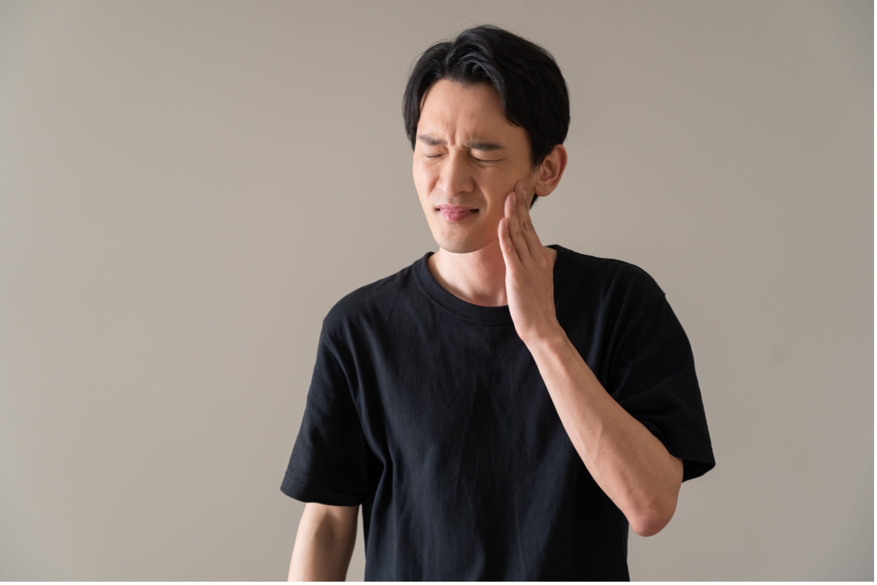 雨の日に頬を押さえて歯の痛みを感じている男性